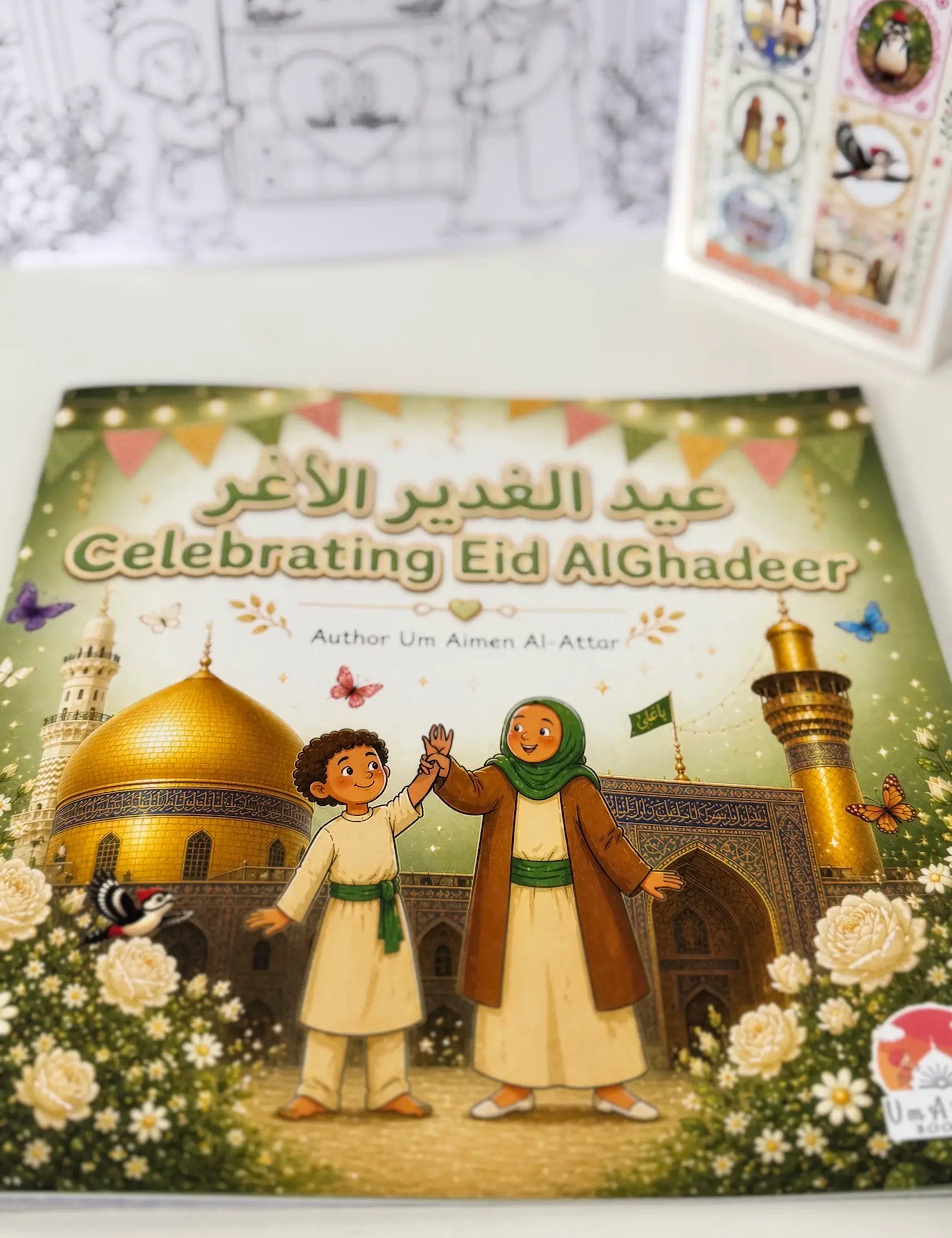 Book titled 'Celebrating Eid AlGhadeer' with illustrations of two children and a mosque on the cover.