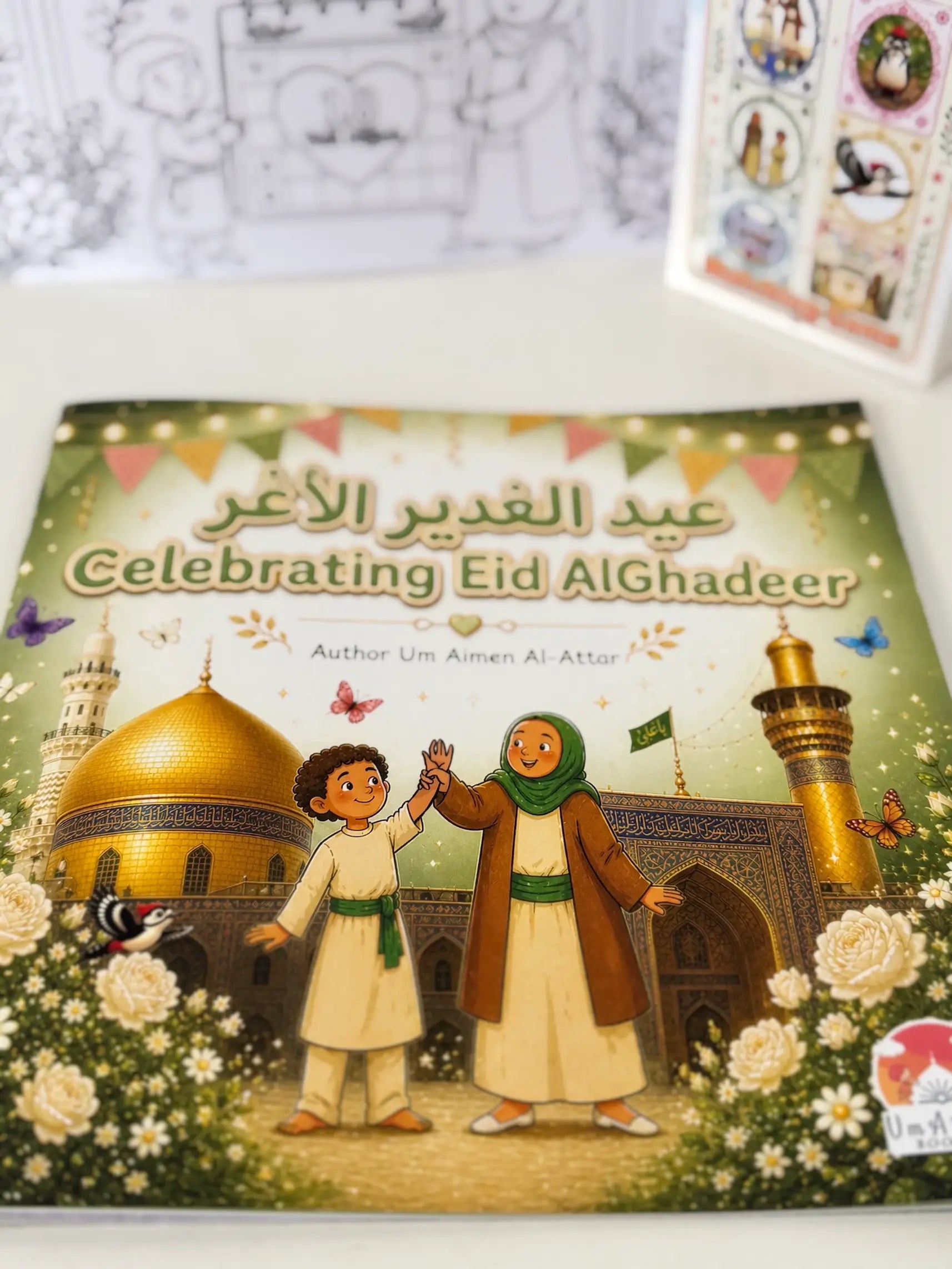 Book titled 'Celebrating Eid AlGhadeer' with illustrations of two children and a mosque on the cover.