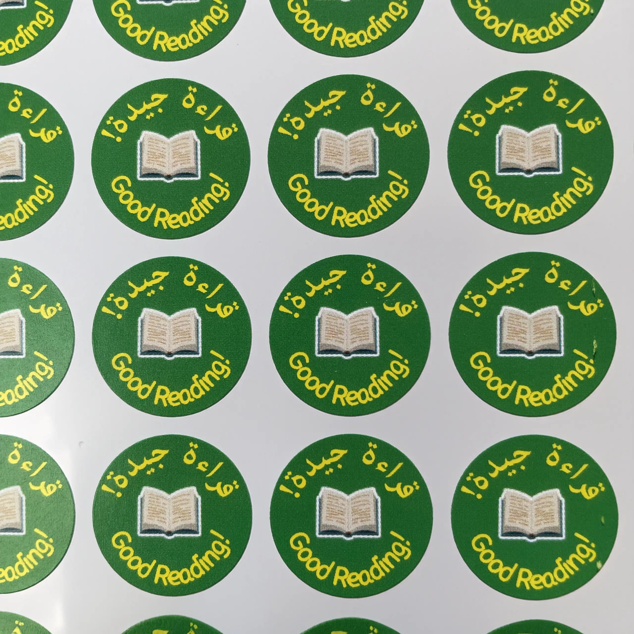 Multiple 'Good Reading!' stickers with green border and white text on a white background in Arabic and english