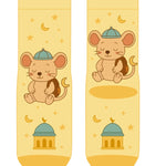 A pair of pale yellow crew socks with a cartoon mouse wearing a blue cap and brown backpack, surrounded by yellow stars and crescent moons, with a small mosque illustration near the toe.