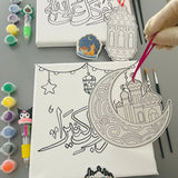 Canvas with crescent moon and star design, paint bottles, and brushes on a gray surface.