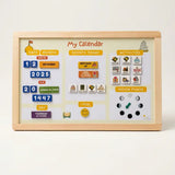 A wooden-framed 'My Calendar' magnetic board with colorful calendar tiles, event stickers, activity icons, and a moon phase tracker, photographed against a clean off-white background.