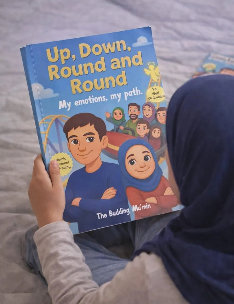 Person holding a children's book titled 'Up, Down, Round and Round' on a bed.