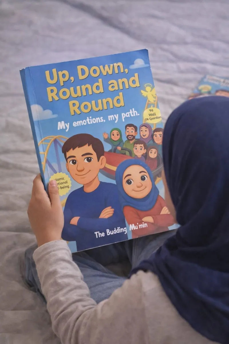 Person holding a children's book titled 'Up, Down, Round and Round' on a bed.