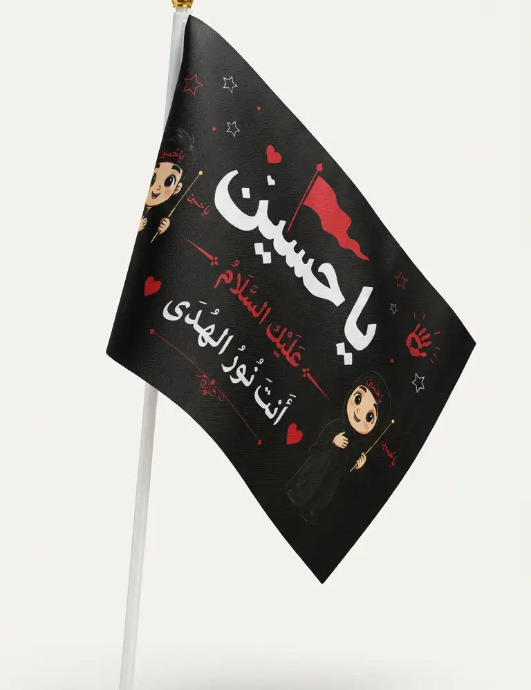 A small black flag on a white stick, featuring Arabic text in white and red with cartoon children and red hearts, shown against a light gray background.