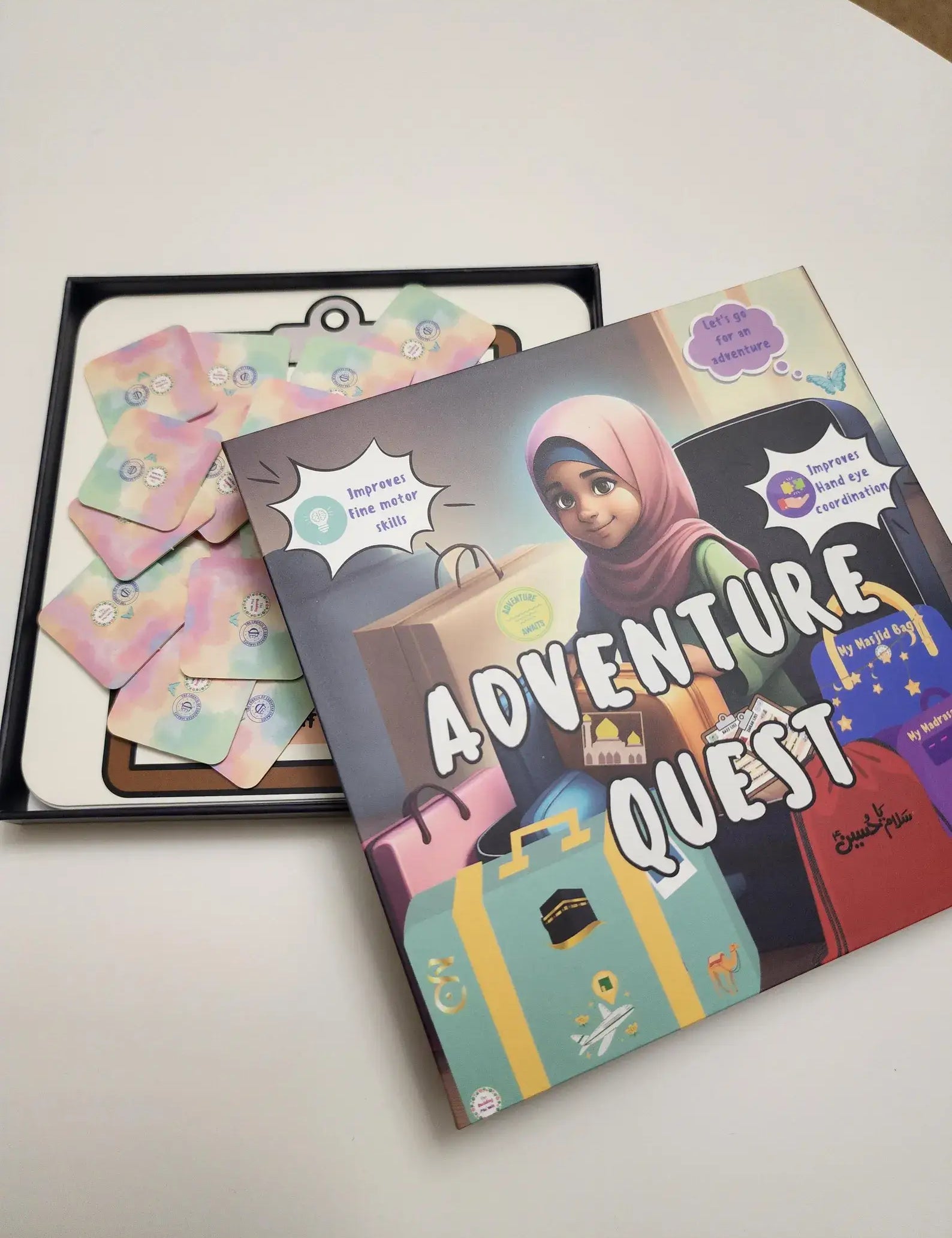 Children's game titled 'Adventure Quest' by Budding Mumin with colourful cover on a white surface with a book