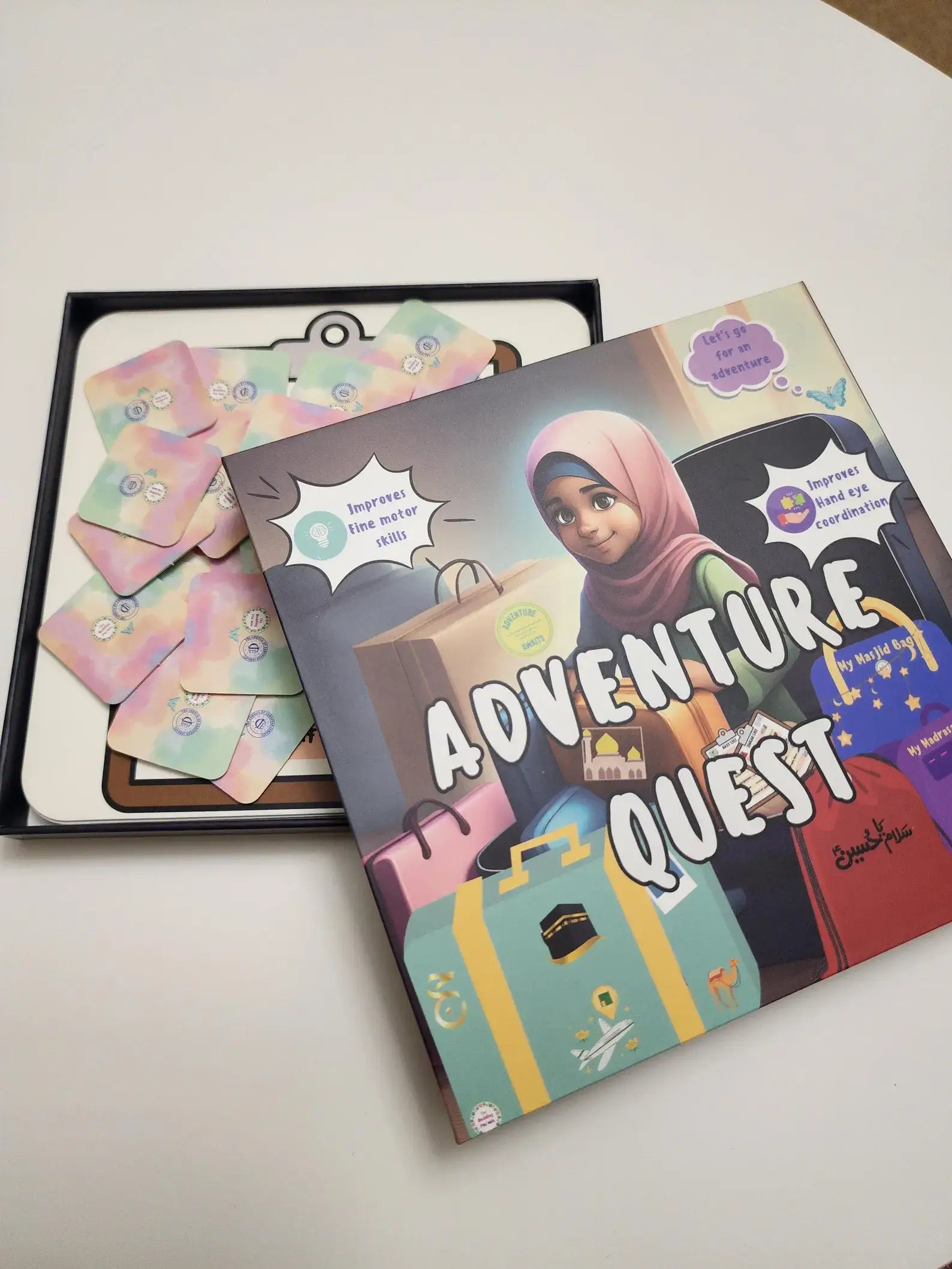 Children's game titled 'Adventure Quest' by Budding Mumin with colourful cover on a white surface with a book