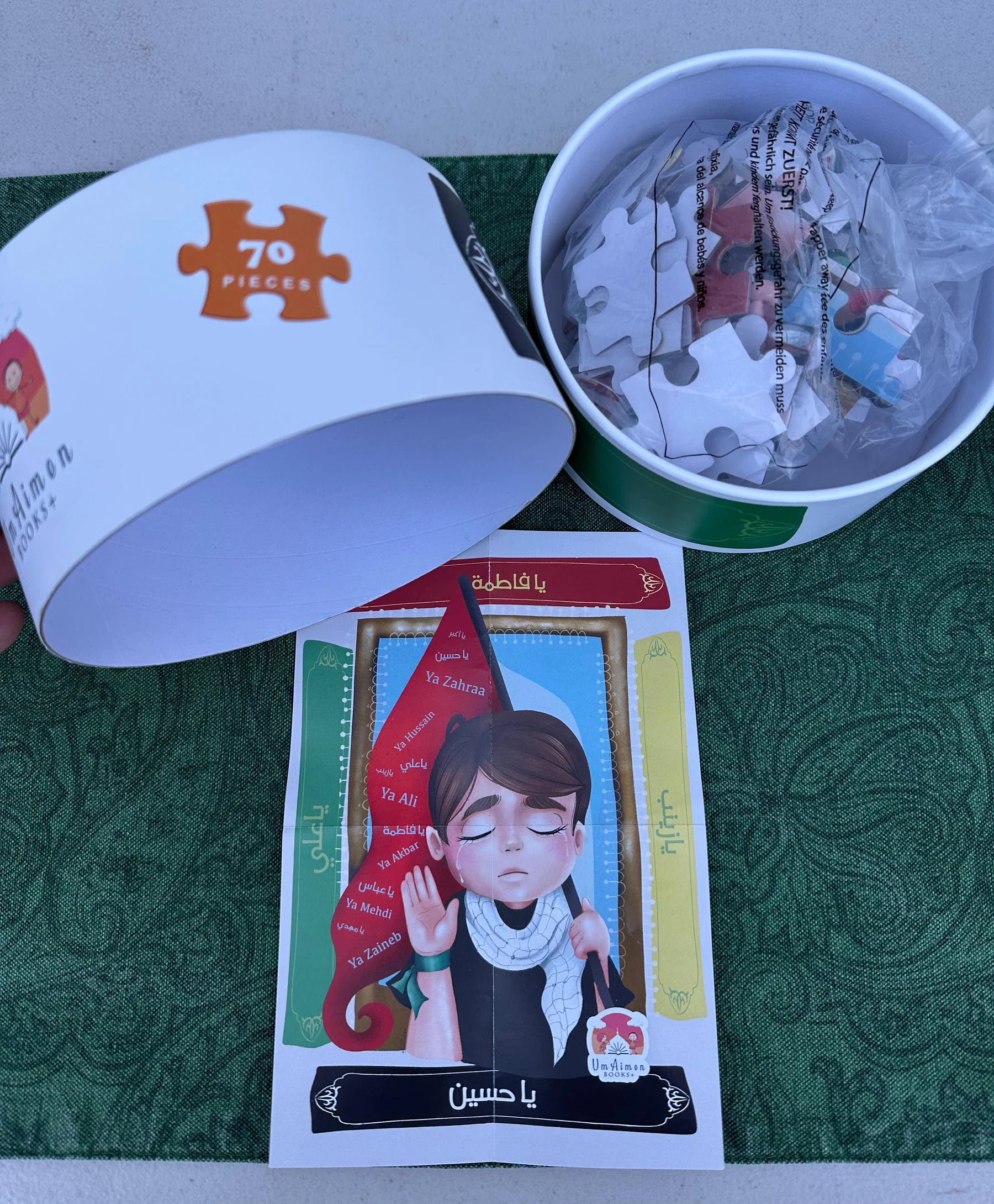 Jigsaw puzzle pieces in a container, a card with a character illustration, and a box labeled '700 pieces' on a green surface.