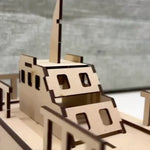 Wooden model of a ship on a reflective surface with a blurred background