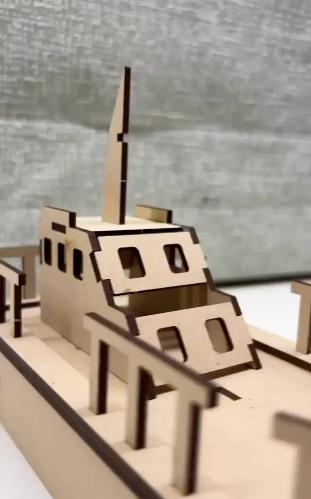 Wooden model of a ship on a reflective surface with a blurred background