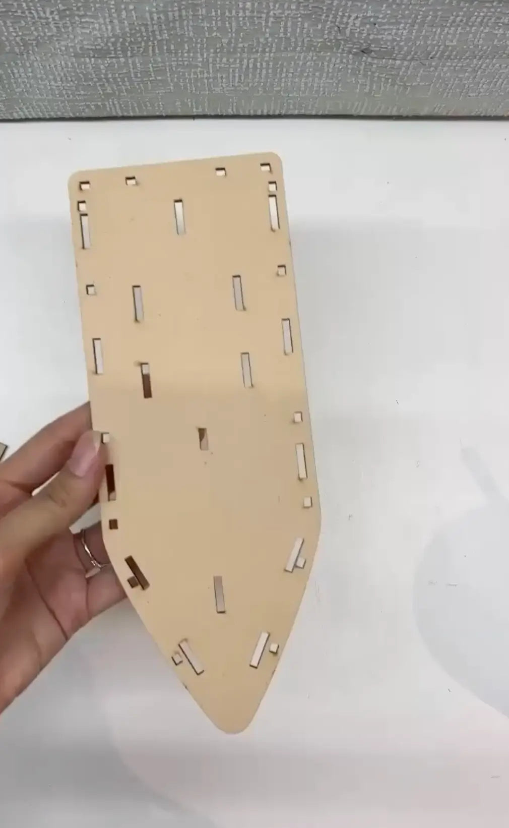 Wooden puzzle piece held by a hand on a white background