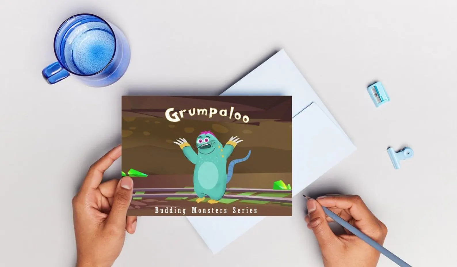 Book with 'Grumpaloo' design held by a hand on a light gray background