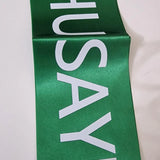 Green sash with 'HUSAYNI' printed in white on a white background