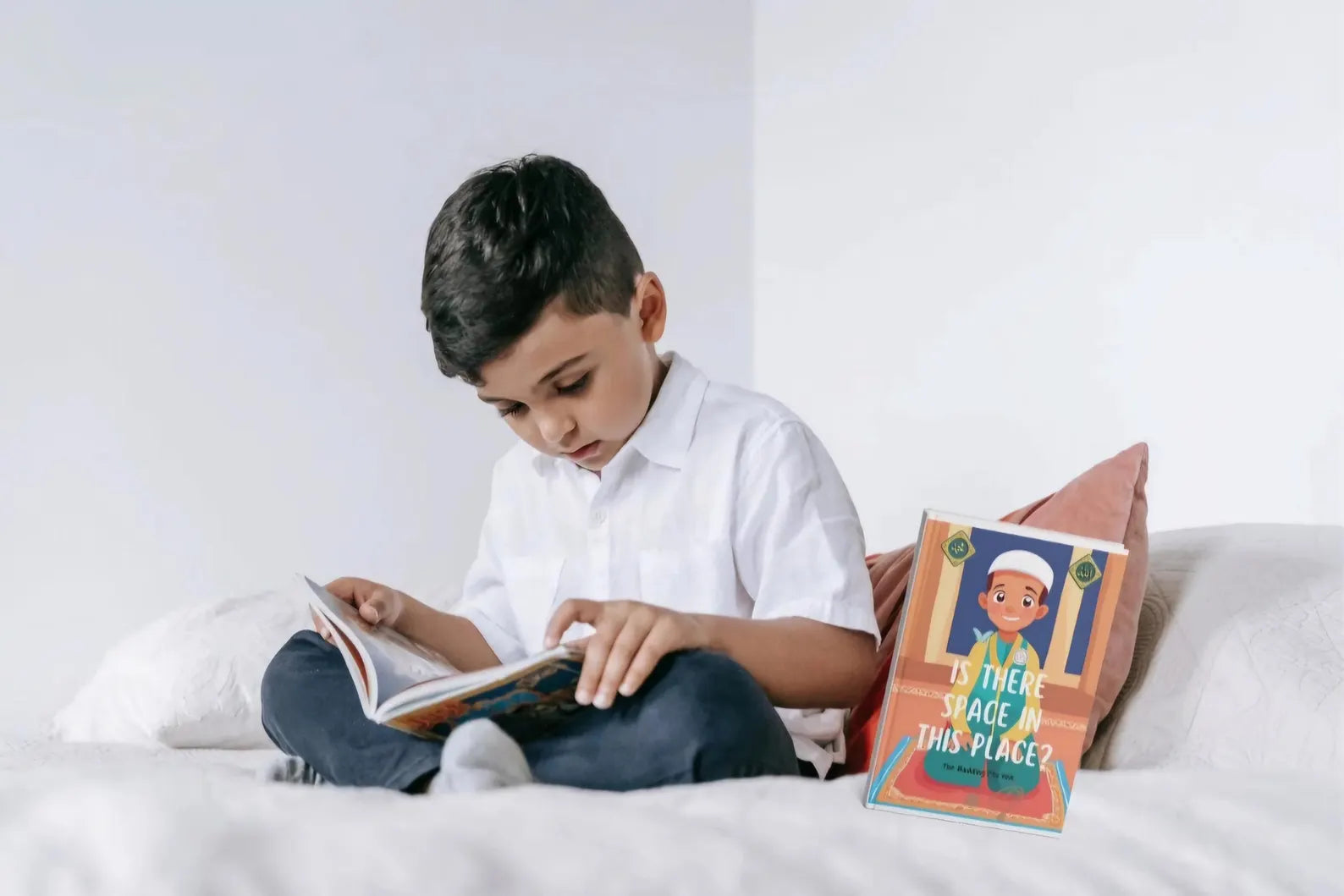 Child reading a book on a bed with a pillow featuring a cartoon character.