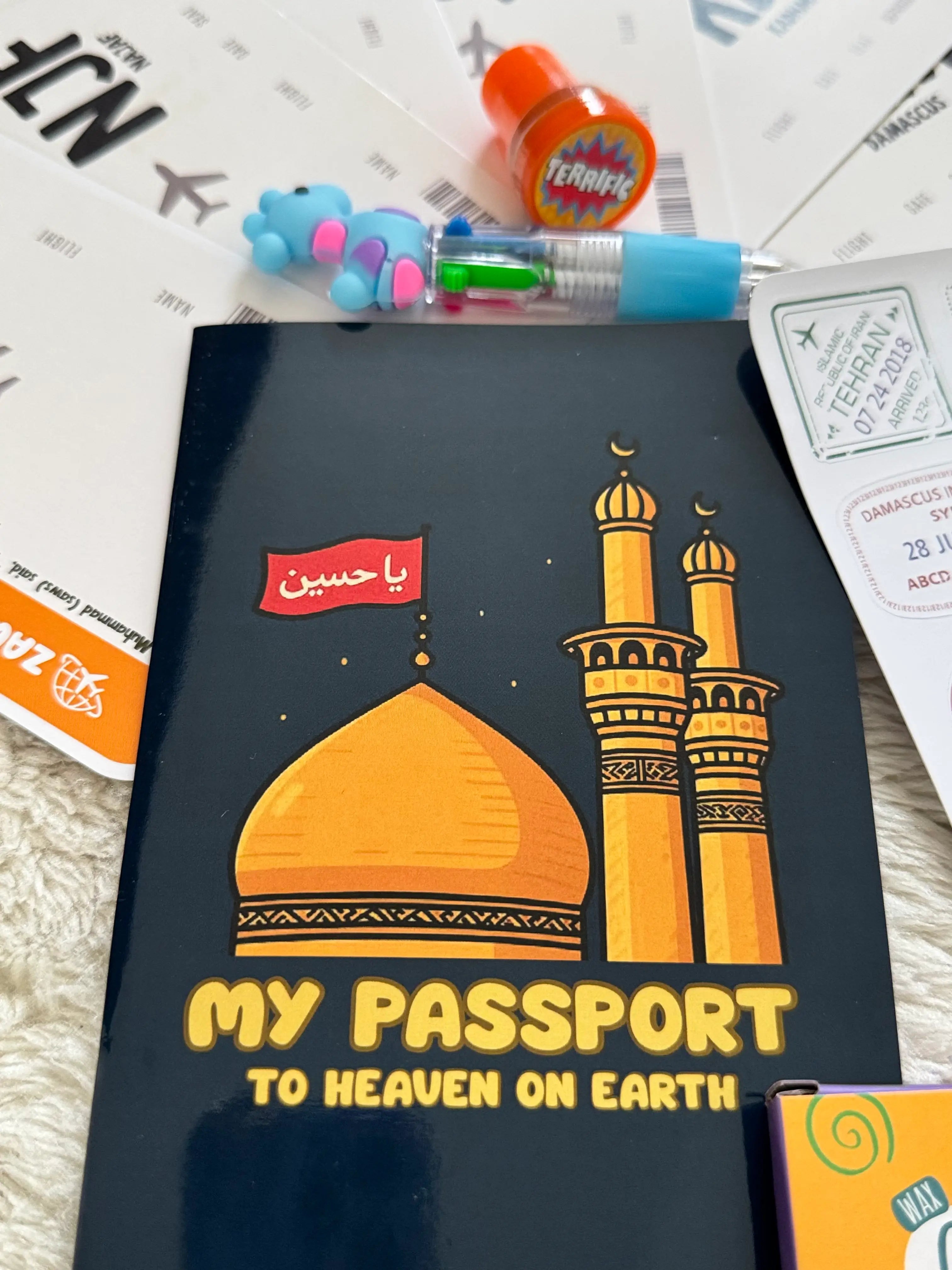 Black book with mosque illustration and text on a surface with stationery items