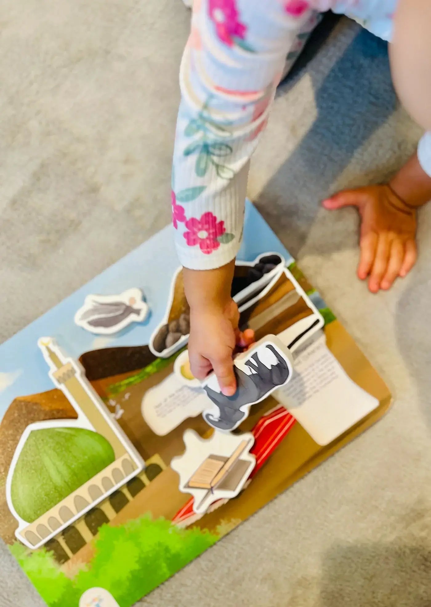 Child playing with Prophet Muhammad puzzle on a beige carpet