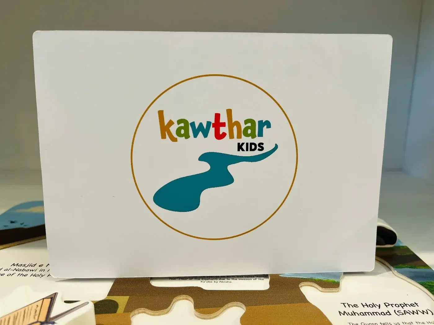 White board with 'Kawthar Kids' logo on a table