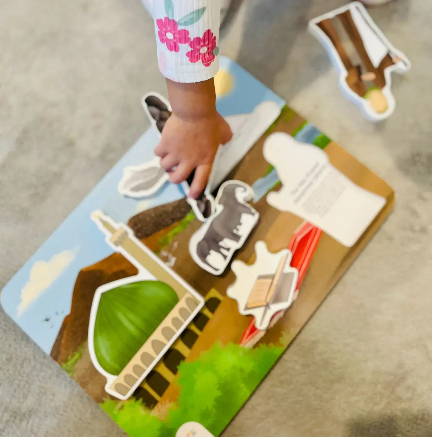 Child playing with a Prophet Muhammad puzzle on a wooden board.