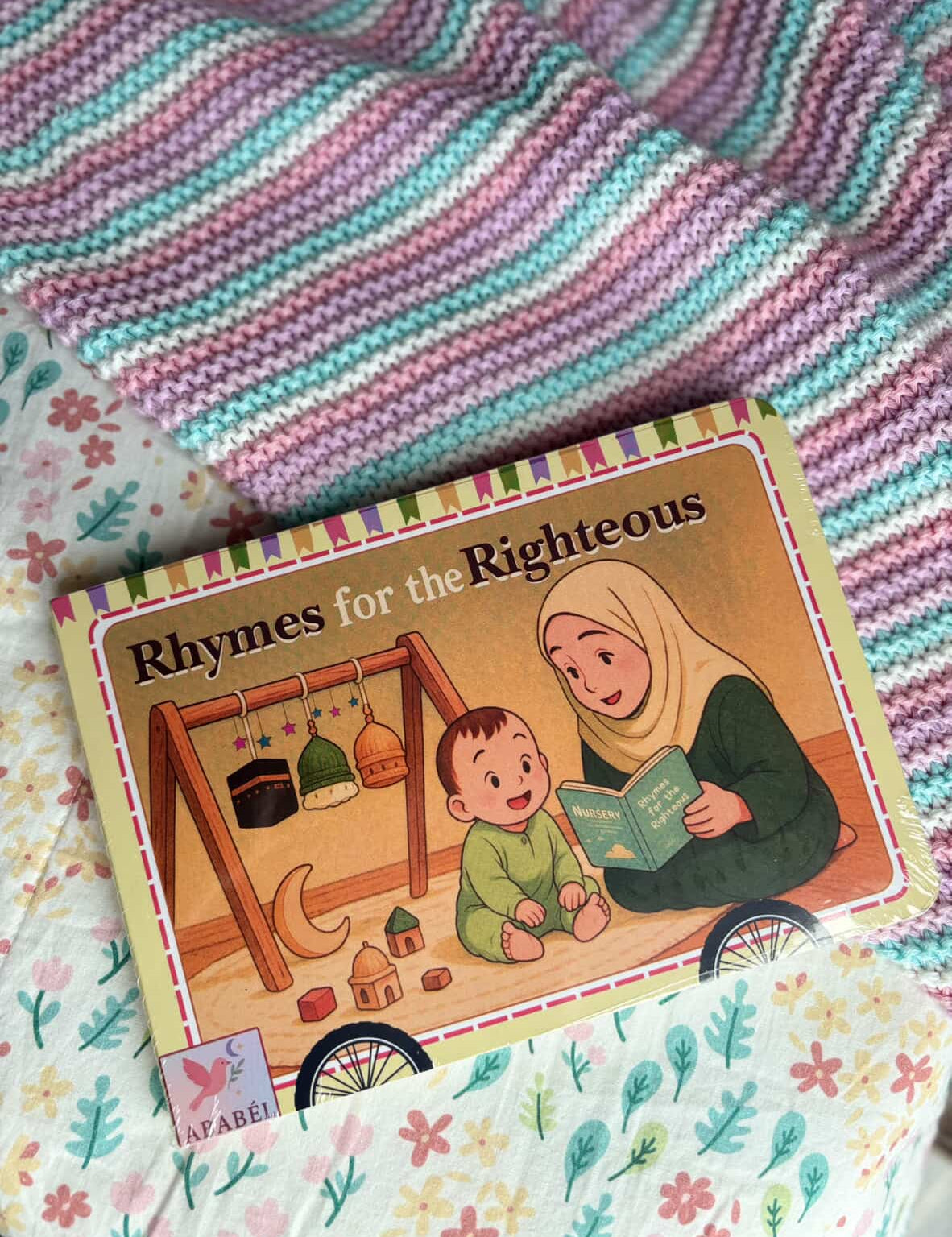 Children's book titled 'Rhymes for the Righteous' on a colourful blanket. Book for toddlers and babies