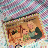 Children's book titled 'Rhymes for the Righteous' on a colourful blanket. Book for toddlers and babies