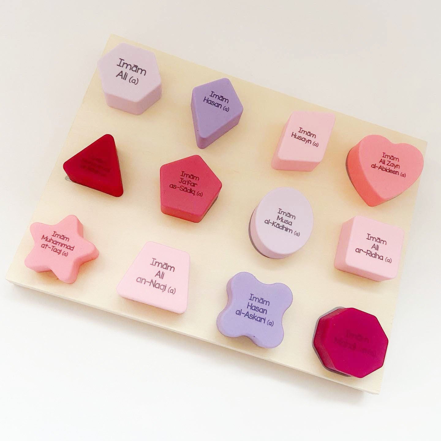 A silicone shape sorter set with shapes and names of the Holy Imams printed on them, displayed on a white background.