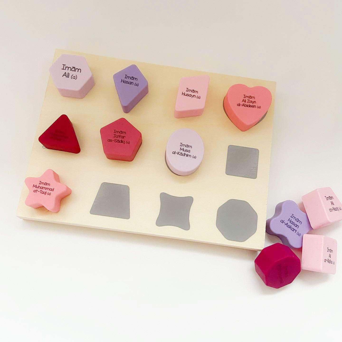 A silicone shape sorter set with shapes and names of the Holy Imams printed on them, displayed on a white background. BY For my Imaan