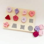A silicone shape sorter set with shapes and names of the Holy Imams printed on them, displayed on a white background. BY For my Imaan