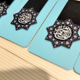 Decorative items with "Ya Qaim Aale Muhammad" calligraphy on a light blue background